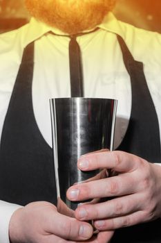 The hands of a professional bartender man holds a tool for mixing and making shaker cocktails.