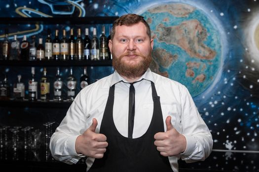 Adult bearded man of European appearance professional bartender shows hand gesture class cool.