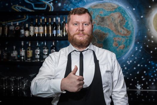 Adult bearded man of European appearance professional bartender shows hand gesture class cool.