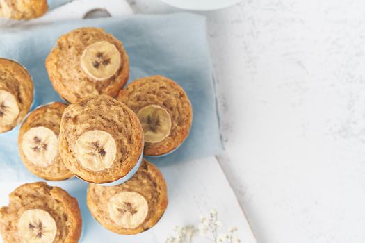 Banana muffin, top view, close up, copy space. Morning breakfast on a blue napkin, white concrete table