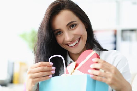 Portrait of brunette female happy to open festive box with present, curious and cheerful look. Gift for birthday, anniversary, event. Celebrate concept