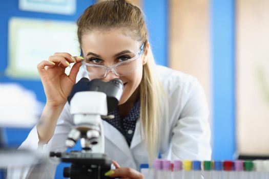 Portrait of clever laboratory lady in medical gown investigate sample under microscope tool. Female chemist in glasses. Science, explore, discovery concept
