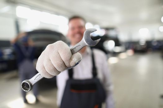 Close-up of service worker hold wrench equipment, metal tool to fix vehicle. Provide high quality machine service on station. Pit stop, maintenance concept