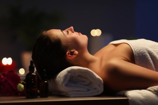 Portrait of relaxed girl lay with closed eyes on massage table in spa, wait for procedure to begin. Full relaxation in luxury spa center. Wellness concept