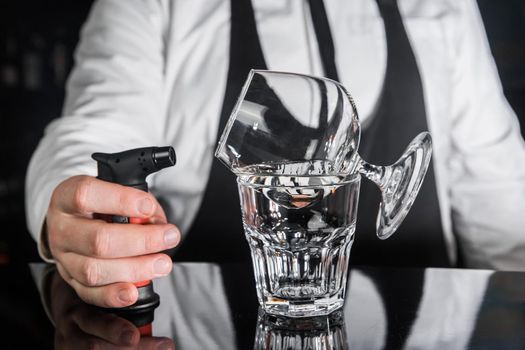 The process of preparing an alcoholic hot cocktail with Italian liqueur of a drink in sambuca glass.