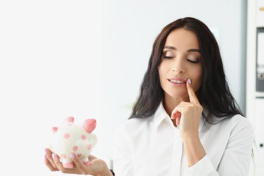 Portrait of woman hold piggybank, think of better way to use money, saving up for future. Female saving for shopping. Investment, saveup, finance concept
