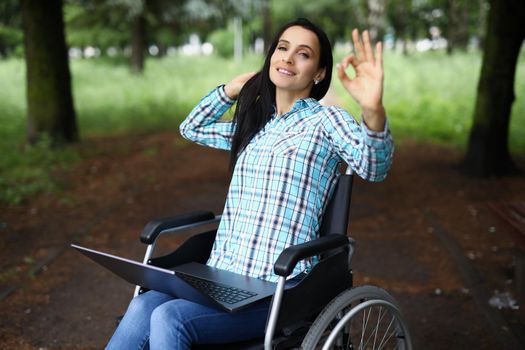 Portrait of woman in wheelchair show ok gesture with hand, work during rehabilitation. Disabled people, recovery, remote job, freelancer, positive concept