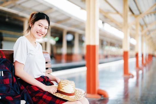 summer, relax, vacation, travel, portrait of cute Asian girl showing smile and showing joy while waiting at the train station for a summer trip