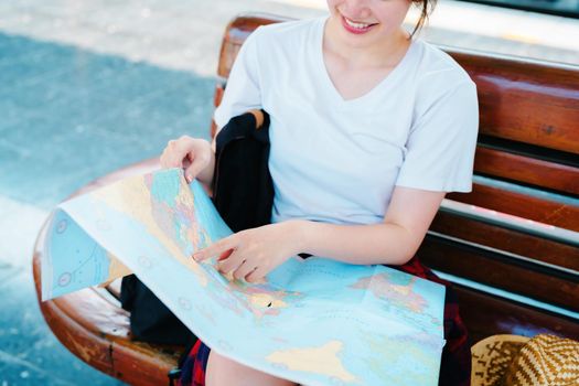 summer, relax, vacation, travel, portrait of a cute Asian girl looking at a map to plan a trip while waiting at the train station