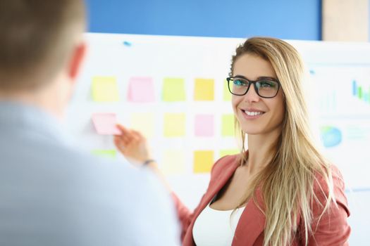 Portrait of businesswoman put colourful stickers on board, prepare presentation, set goals for next year. Female go through strategy. Business, aim concept