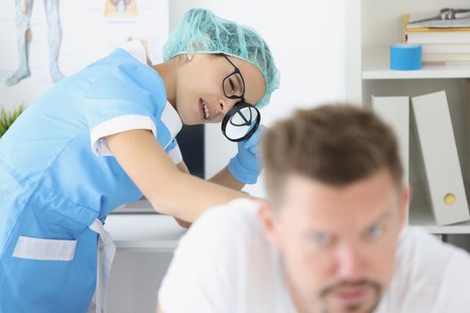 Portrait of woman dermatologist examine male patient body, check skin on back with magnifying glass. Client on appointment in clinic. Healthcare concept