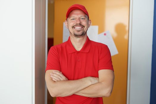 Portrait of happy man courier in red shirt and cap uniform, delivery worker. Best worker, positive and energetic. Delivery company, private courier concept