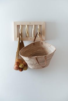 straw bag and mesh bag on handmade wooden hang. Concept of slowlife home. High quality photo