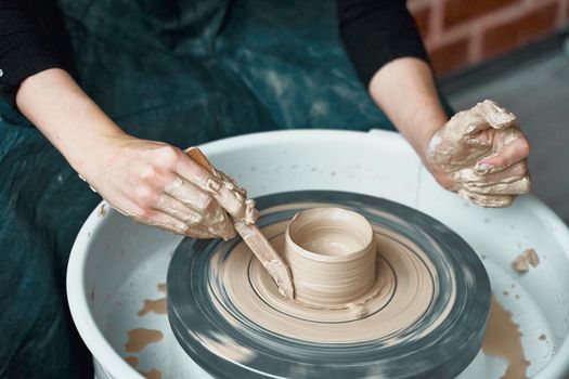 Woman making ceramic pottery on wheel, hands close-up, creation of ceramic ware. Handwork, craft, manual labor, buisness. Earn extra money, turning hobbies into cash and turning passion into a job