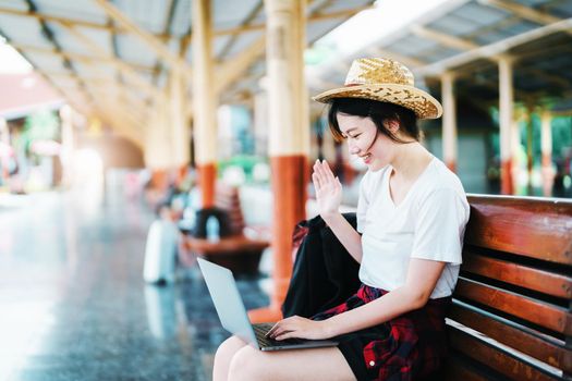 summer, relax, vacation, travel, portrait of beautiful Asian girl using the computer laptop at the train station while waiting for their travel time