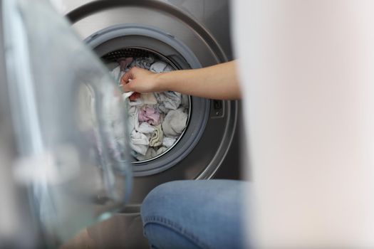 Close-up of woman loading washing machine with dirty clothes, taking out clean stuff. Household, bathroom, domestic chores, cleaning day, housewife concept