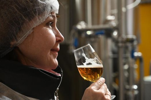 Woman in overalls tasting beer with a smile
