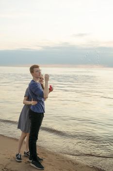 boyfriend and girlfriend blow bubbles standing on the beach, sea ocean on background