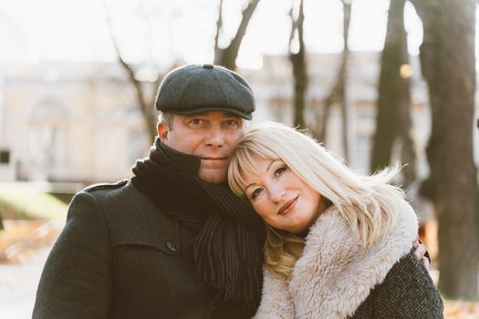 Closeup portrait of happy blonde mature woman and beautiful middle-aged brunette, looking looking directly at the camera. Loving couple of 45-50 years old walks in autumn park in warm clothes