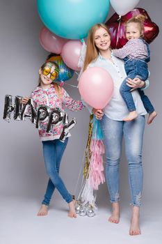 the child in the arms of his mother on a white background. A woman with a child in her arms holding festive balloons