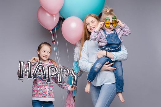 the child in the arms of his mother on a white background. A woman with a child in her arms holding festive balloons