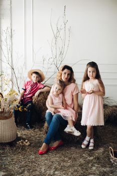 Portrait of cute family looking at camera and smiling at home. Young attractive mother posing with son and cute daughters. Lovely family hugging each other. Concept of love and motherhood.