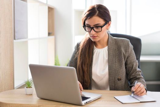 front view businesswoman working laptop office