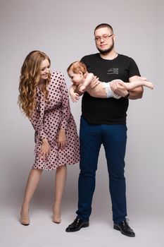 Portrait of happy family from three people wearing same coloured clothes. Blonde beautiful mother smiling surprised child. Handsome father in glasses hugging lovely wife and son.