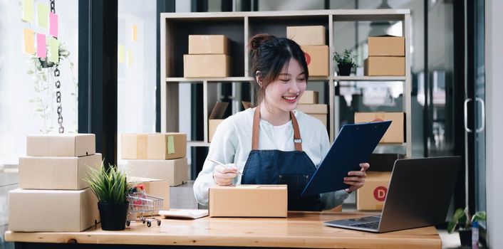 Starting small businesses SME owners is writing addresses to prepare boxes for sale to customers. She was happy after the new order from the customer. Online sme business ideas..