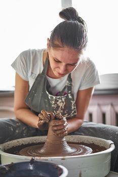 Beautiful woman making ceramic pottery on wheel, hands close-up. Concept for woman in freelance, business, hobby