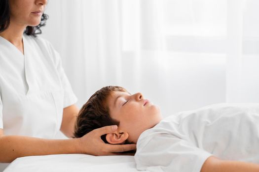 osteopathist treating kid by massaging his head