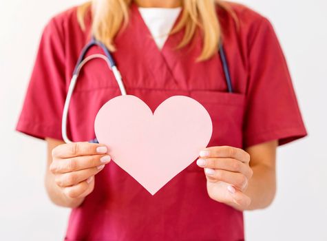 front view female doctor with stethoscope holding paper heart