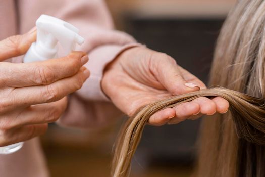 hairdresser holding tuft hair spraying with water