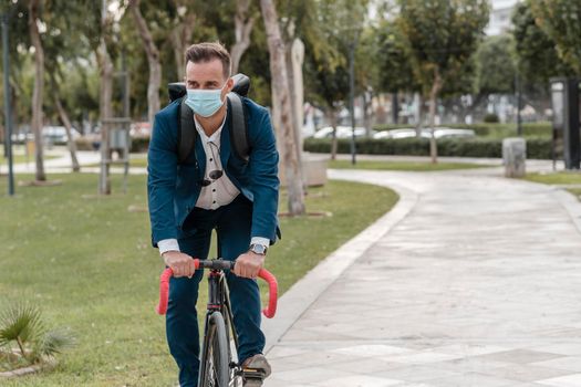 man riding bike while wearing medical mask