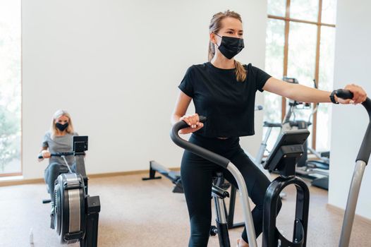 women with medical mask during pandemic exercising gym