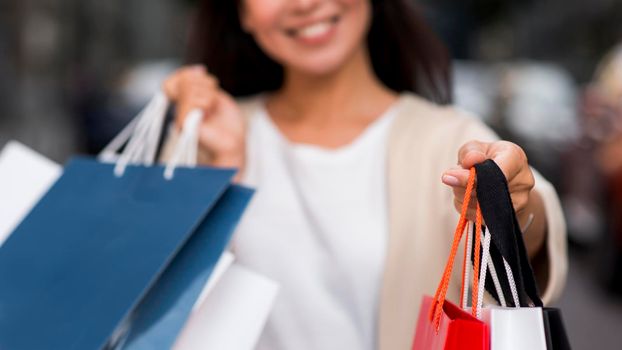 defocused smiley woman holding shopping bags after sale session