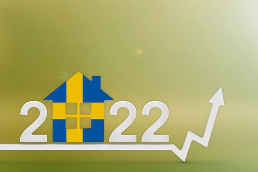 The cost of real estate in Sweden in 2022. Rising cost of construction, insurance, rent in Sweden. 3d House model painted in flag colors, up arrow on yellow background.