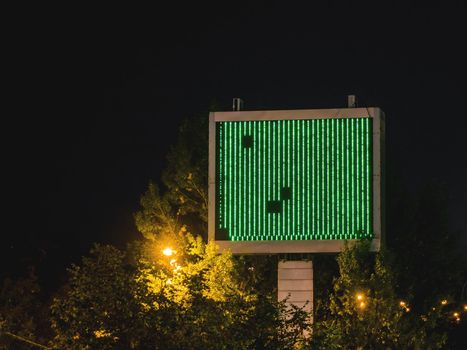 Broken outdoor advertising screen. Electronic device for showing commercials on the street. Green interference on the display at night.