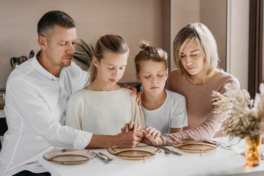 family praying while holding their hands together