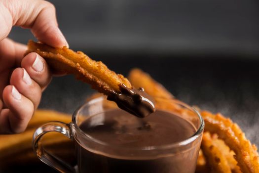 hand dipping fried churros chocolate