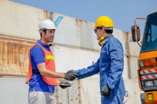 Technician and engineer shake hand in cargo container area with concept collaborate working.