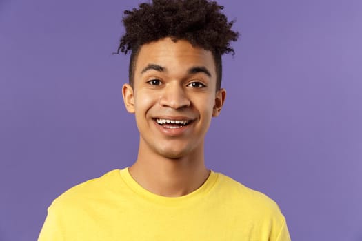 Close-up portrait of cheerful smiling man looking happy, express enthusiastic optimistic emotions, seeing something pleasant and interesting, standing purple background.