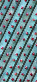 Red pomegranate seeds on a turquoise background. Diagonal line texture, top view. Background wallpaper for phone.