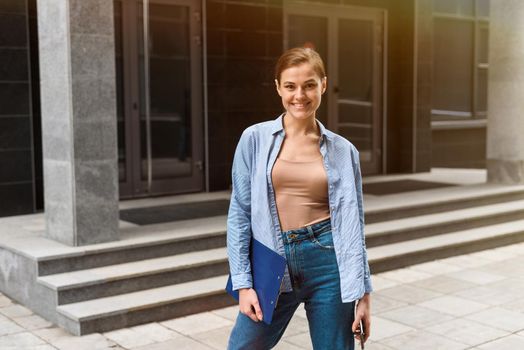 Successful young businesswoman checks email on smartphone during a lunch break outside office. City businesswoman working.