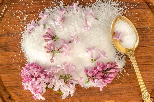 Lilac flowers and sugar on a wooden board. From the series Cooking lilac syrup