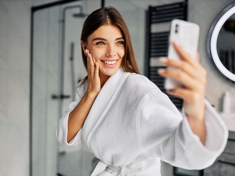 positive young woman bathrobe taking selfie