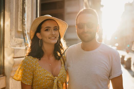 A close photo of a man with a beard and his girlfriend in a hat and a yellow dress with a plunging neckline in Spain. A couple of lovers on a date on the sunset in Valencia.