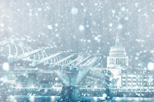 View of St. Paul Cathedral and Millennium Bridge in London by night with snow