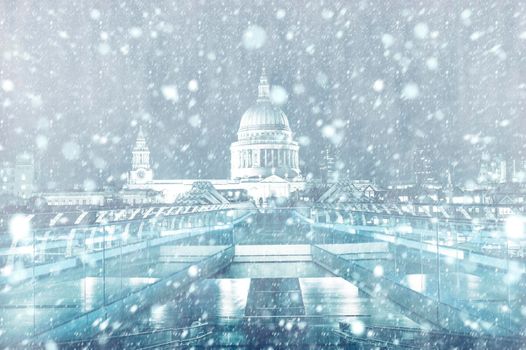 View of St. Paul Cathedral and Millennium Bridge in London by night with snow