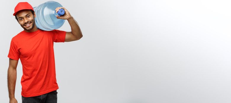 Delivery Concept - Handsome African American delivery man holding water tank. Isolated on Grey studio Background. Copy Space